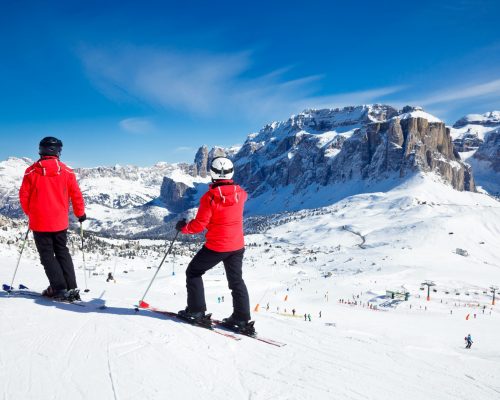 Skiers overlooking the piste at Val Di Fassa ski resort in Italy